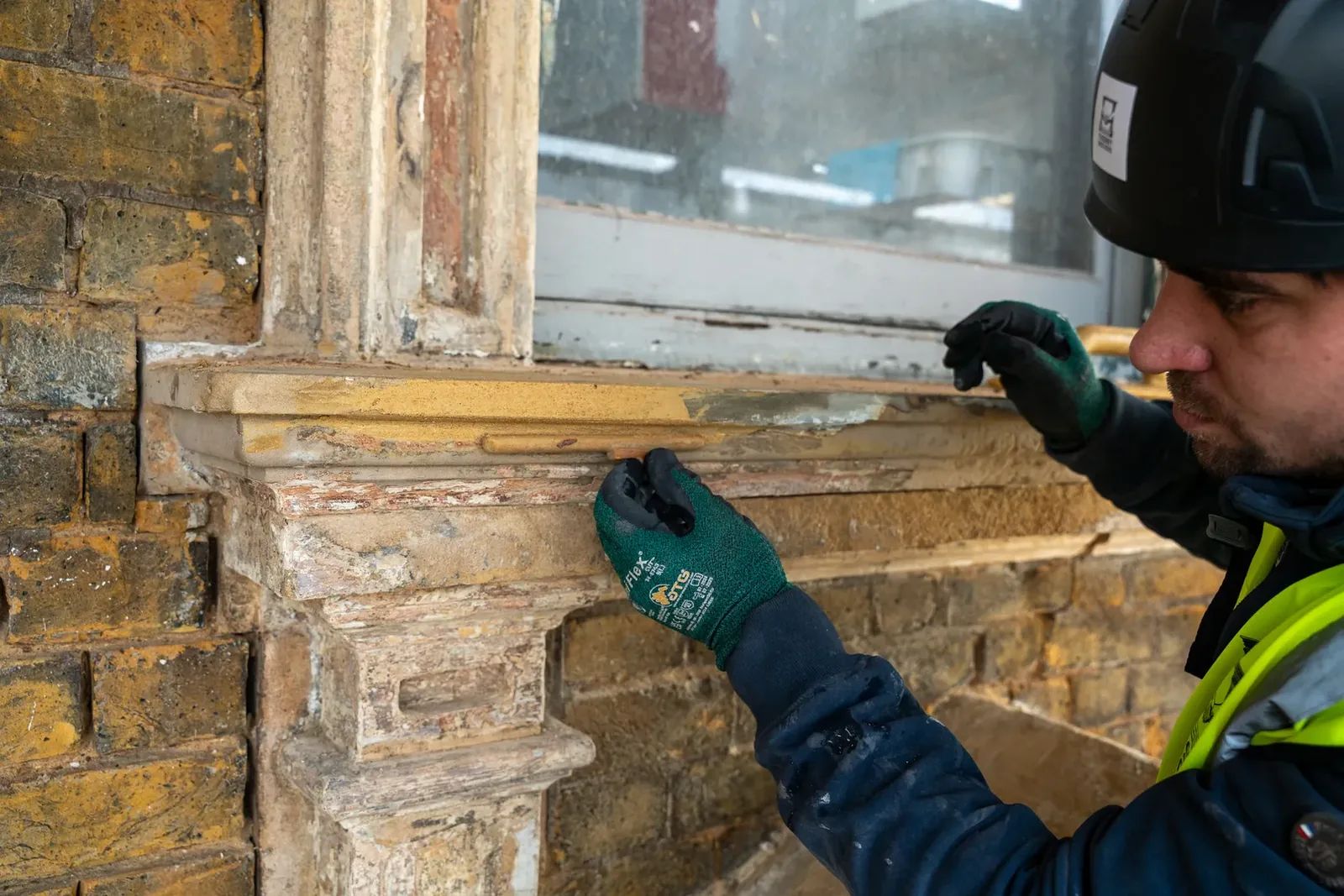 Worker inspecting stone window sill during restoration project